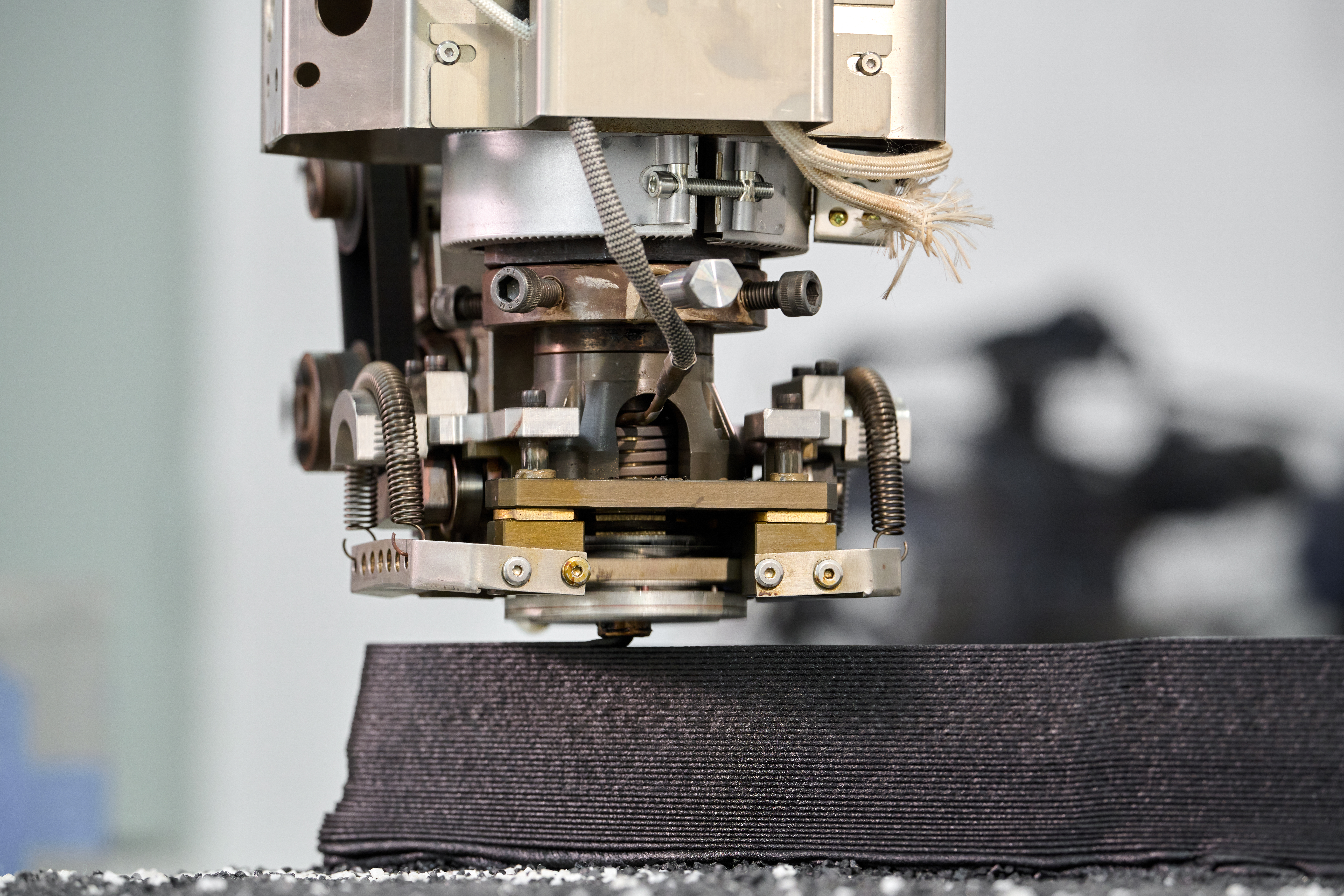 Close-up of a large-format extrusion head depositing a thick bead onto a part.